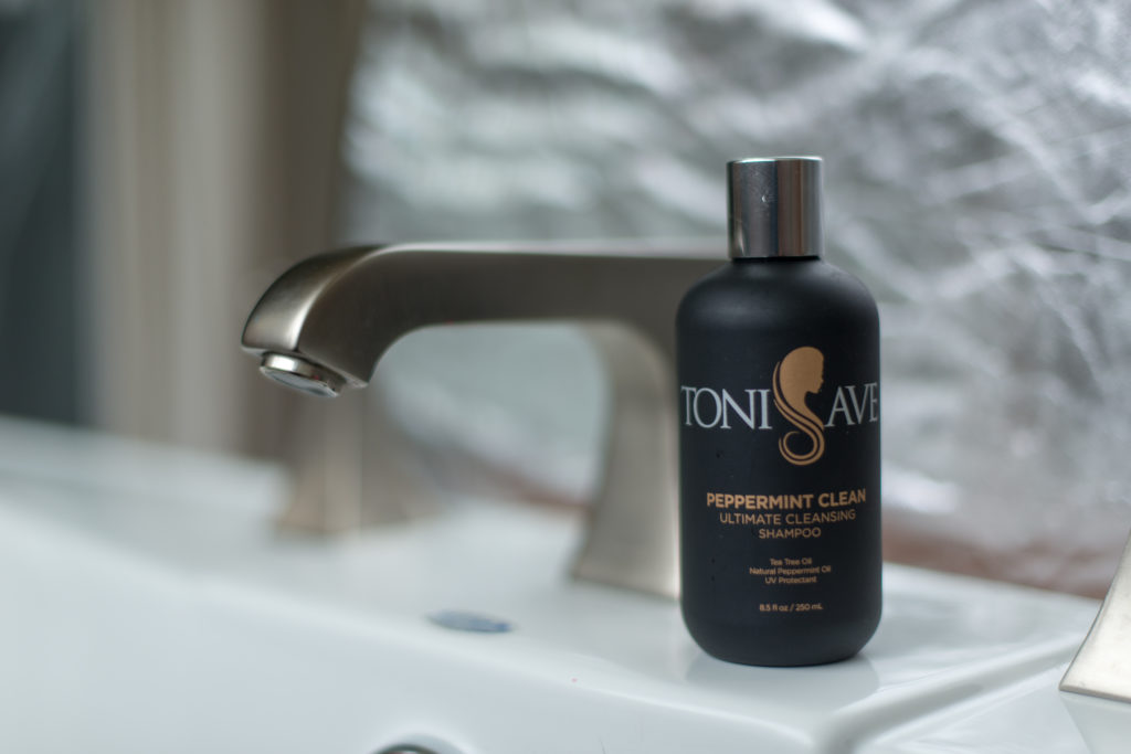 Toni Save Peppermint Clean Ultimate Cleansing Shampoo bottle placed on a bathroom sink beside a silver faucet.